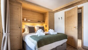 Un dormitorio con cabecera de madera, cama con ropa de cama blanca y manta verde.