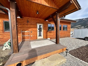 A wooden cabin with a covered porch, a door, and windows.