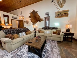 A spacious living room with two sofas, a coffee table, and a large wall-mounted animal hide.