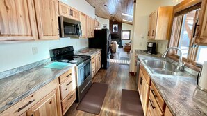 A kitchen with wooden cabinets, a stainless steel stove, and a large window. - NEW! LAST MINUTE SPECIAL! Spacious Modern Chalet, Close To Everything Big Sky, MT! (Big Sky)