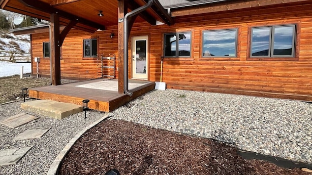 A modern log cabin with a covered porch, large windows, and a gravel driveway. - NEW! LAST MINUTE SPECIAL! Spacious Modern Chalet, Close To Everything Big Sky, MT! (Big Sky)