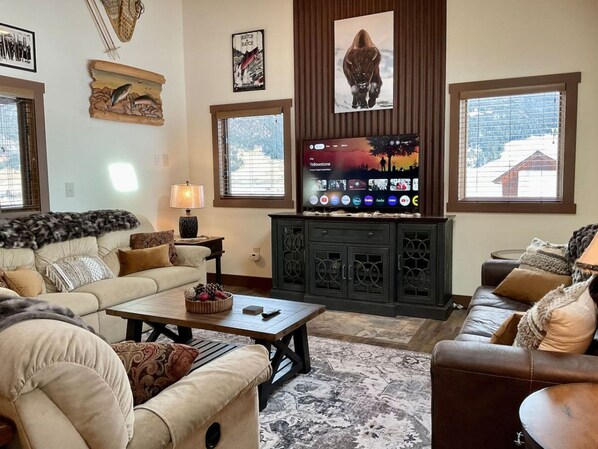 A cozy living room with a fireplace, a flat-screen TV, and a large window.