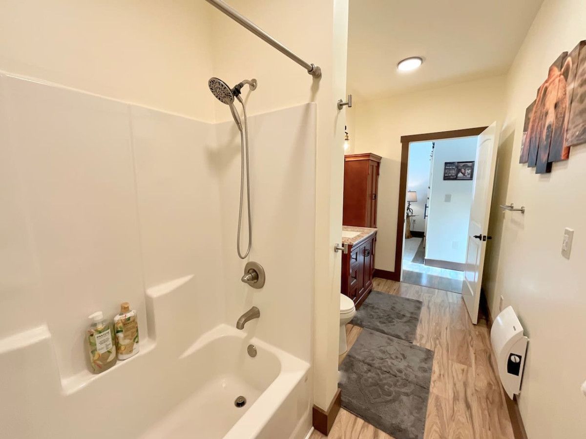 A bathroom with a bathtub, shower, and toilet. There are two bottles on the wall.