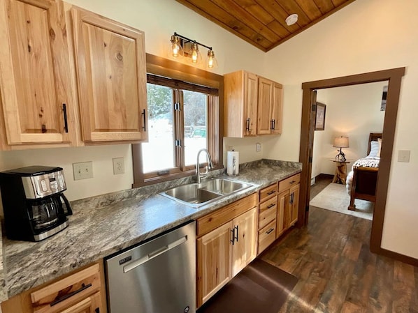 A kitchen with wooden cabinets, a stainless steel sink, and a coffee maker.