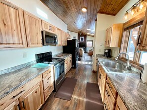 A kitchen with wooden cabinets, a stainless steel stove, and a large window.