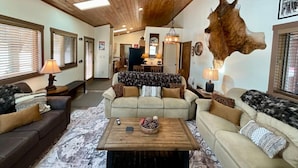 A cozy living room with a wooden ceiling, two sofas, a coffee table, and a large animal hide on the wall. - NEW! LAST MINUTE SPECIAL! Spacious Modern Chalet, Close To Everything Big Sky, MT! (Big Sky)