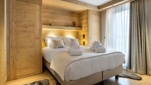 Une chambre à coucher aux murs lambrés, avec un lit, des oreillers et des serviettes.