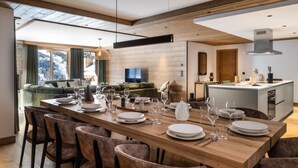 A modern dining area with a wooden table set for six, surrounded by upholstered chairs. - Wifi, 150m from ski slopes, Ground floor, sauna, hammam, terrace, balcony, tv, 182m², Méribel (Méribel - Les Allues)
