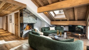 A modern loft with a fireplace, green sofas, a flat-screen TV, and wooden beams. - Wifi, 150m from ski slopes, 2nd floor, sauna, hammam, balcony, fireplace or stove, tv, 74m², Méribel (Méribel - Les Allues)