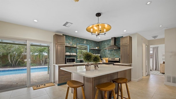 A modern kitchen with a large island, bar stools, and a view of a swimming pool. - HUGE HEATED SALT POOL! NEAR DOWNTOWN! TV IN EVERY BEDROOM! (Sarasota)