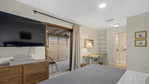 A modern hotel room with a large bed, a desk, a chair, a TV, and a sliding door to a balcony. - HUGE HEATED SALT POOL! NEAR DOWNTOWN! TV IN EVERY BEDROOM! (Sarasota)