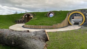 A circular stone structure with a wooden deck and a stone bench. - Honeybee Home -  a hobbit hut that sleeps 4 guests  in 2 bedrooms (Llansantffraid)
