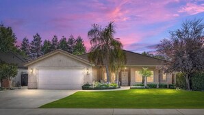 A single-story house with a garage, a well-maintained lawn, and a driveway. - Charming spacious 4 Bed house with WiFi and AC large backyard and pool. (Bakersfield)