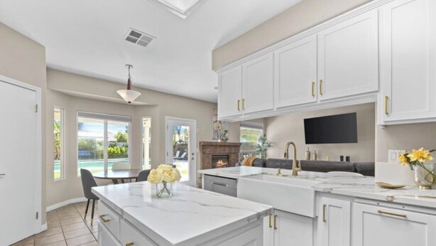 A spacious kitchen with white cabinetry, a large island, and a fireplace. - Charming spacious 4 Bed house with WiFi and AC large backyard and pool. (Bakersfield)