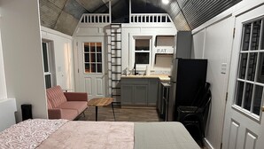 Un espace de vie compact comprenant un coin cuisine, un canapé, une petite table et un lit.