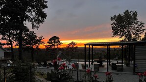 Un espace extérieur aménagé avec une pergola, des sièges et une vue sur le coucher du soleil.