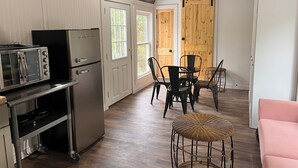 Une cuisine compacte équipée d’un grille-pain, d’un réfrigérateur et d’un coin repas avec des chaises et une table.