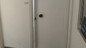 Una puerta blanca con pomo redondo, un pequeño ventanal en la puerta y una señal azul en la pared a la derecha.