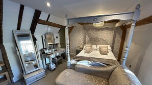 Une chambre à coucher avec un lit à baldaquin, une coiffeuse avec un miroir et une commode.