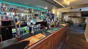 Un espace bar avec un assortiment de bouteilles d’alcool, un choix de robinets et un comptoir en bois.