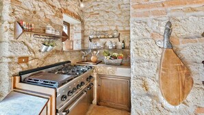 Une cuisine rustique avec un mur en pierre, des poutres en bois et une cuisinière à gaz.