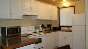 A compact kitchen with white cabinets, a microwave, a stove, and a refrigerator. - Soothing 2-bdrm condo near beach with WiFi and Fireplace (Ocean Shores)