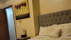 A hotel room with a large bed, a tufted headboard, and a painting on the wall. - Soothing 2-bdrm condo near beach with WiFi and Fireplace (Ocean Shores)