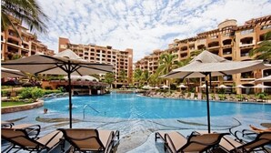 A swimming pool surrounded by lounge chairs and umbrellas, with multi-story buildings in the background. - Penthouse Luxury. WOW! Panoramic views of everything! BradAndJoeyRentals (Nuevo Vallarta)