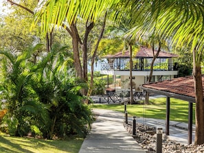 A resort with a pathway, lush greenery, and a building with a red-tiled roof. - Reunion Wellness Resort & Retreats (Tempate)