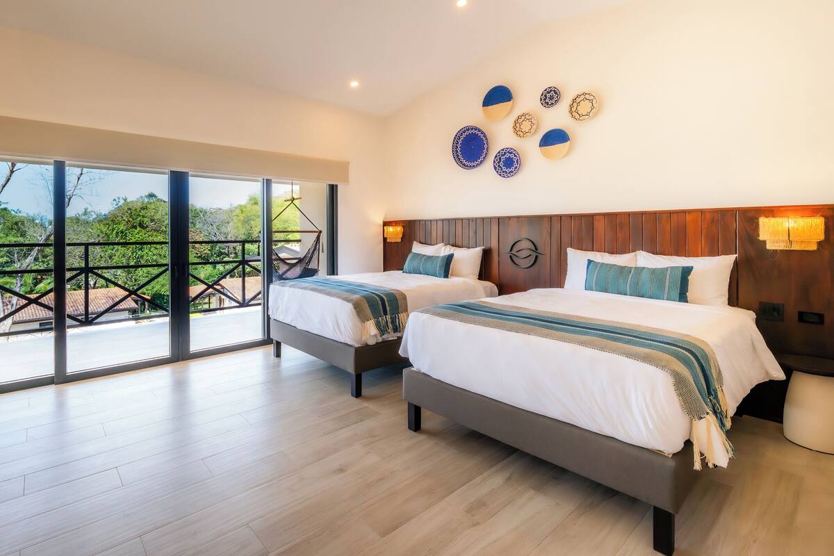 A hotel room with two beds, a balcony with a view, and decorative wall art.