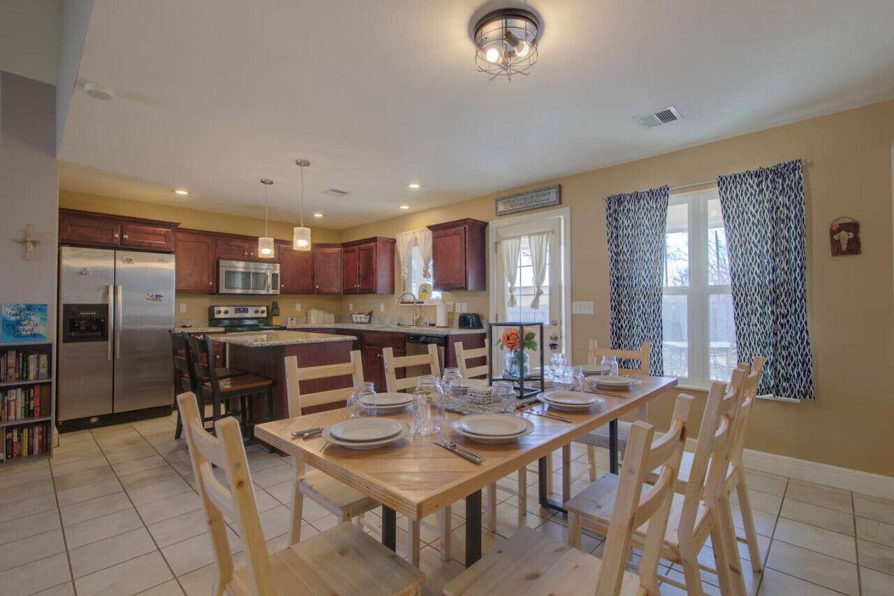 A spacious kitchen with wooden cabinets, a stainless steel refrigerator, and a dining area set for four.