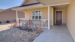 A residential building with a covered porch, a front door, and a small garden area.