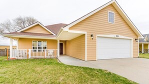 A two-story house with a garage, a covered porch, and a well-maintained lawn.