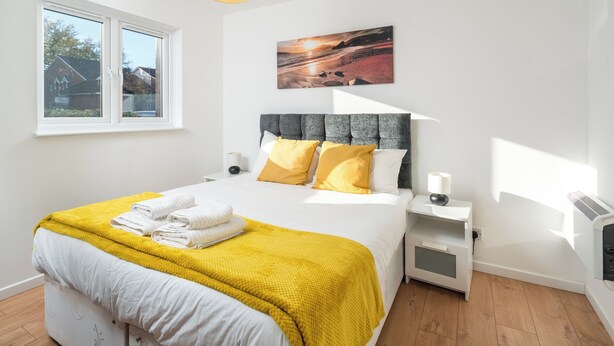 A bedroom with a bed, a window, a bedside table, a nightstand, and a wall-mounted artwork. - Spacious 1 Bedroom Apartment w/ Parking in Crawley (Crawley)