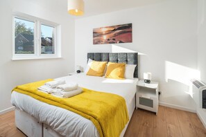 Une chambre à coucher comprenant un lit, une fenêtre, une table de chevet et une étagère, ainsi qu’une œuvre d’art accrochée au mur.