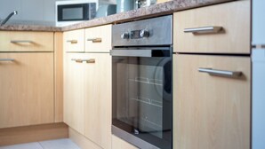 A kitchen with wooden cabinets, a stainless steel oven, and a microwave on the countertop. - Spacious 1 Bedroom Apartment w/ Parking in Crawley (Crawley)