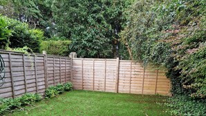 A fenced backyard with a well-maintained lawn and a wooden fence.