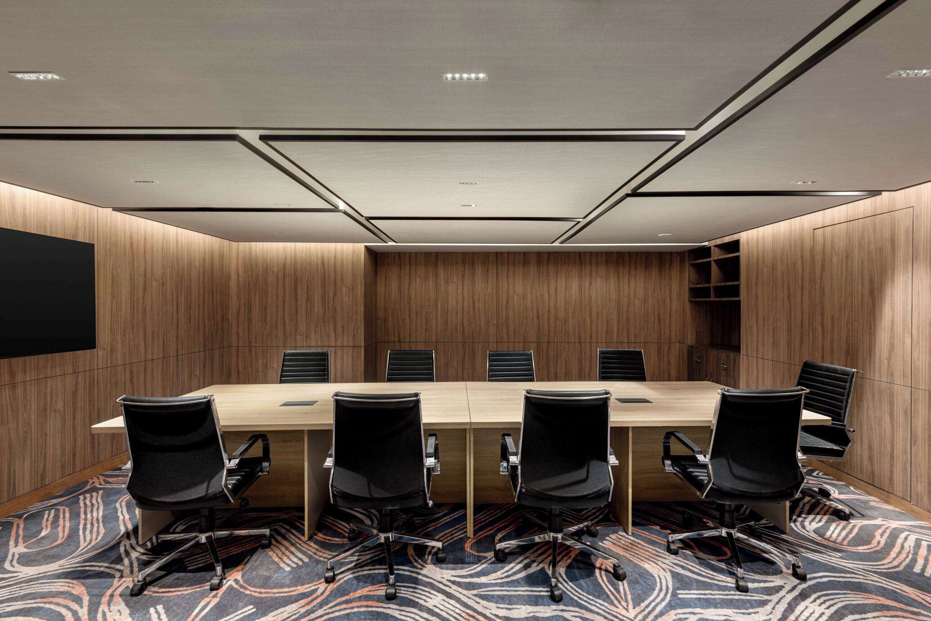 Une salle de conférence avec une longue table, six chaises et un sol recouvert de moquette.