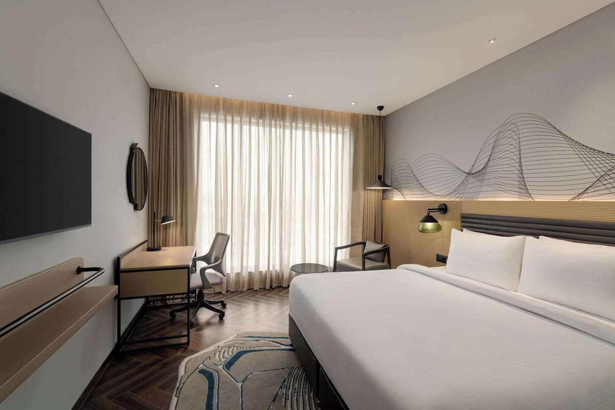 Ein modernes Hotelzimmer mit einem großen Bett, einem Schreibtisch und einem Sessel.
