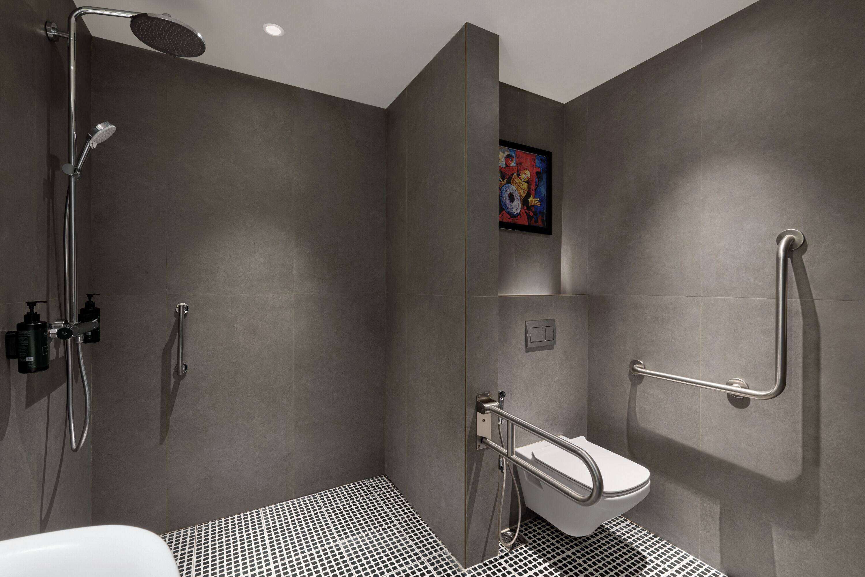 Ein modernes Badezimmer mit Dusche, Toilette und Haltegriffen.