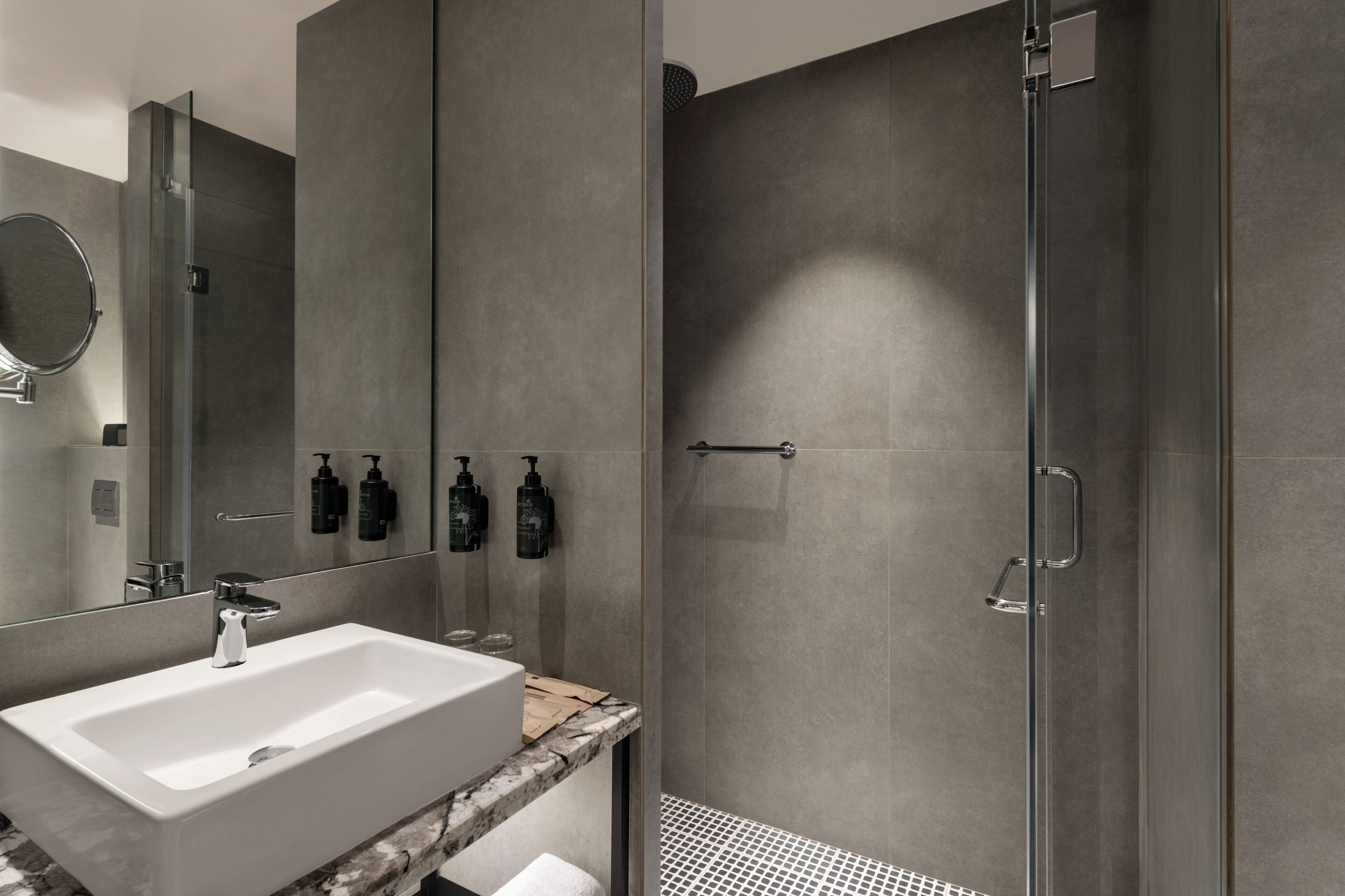 A modern bathroom with a large sink, mirror, and shower.