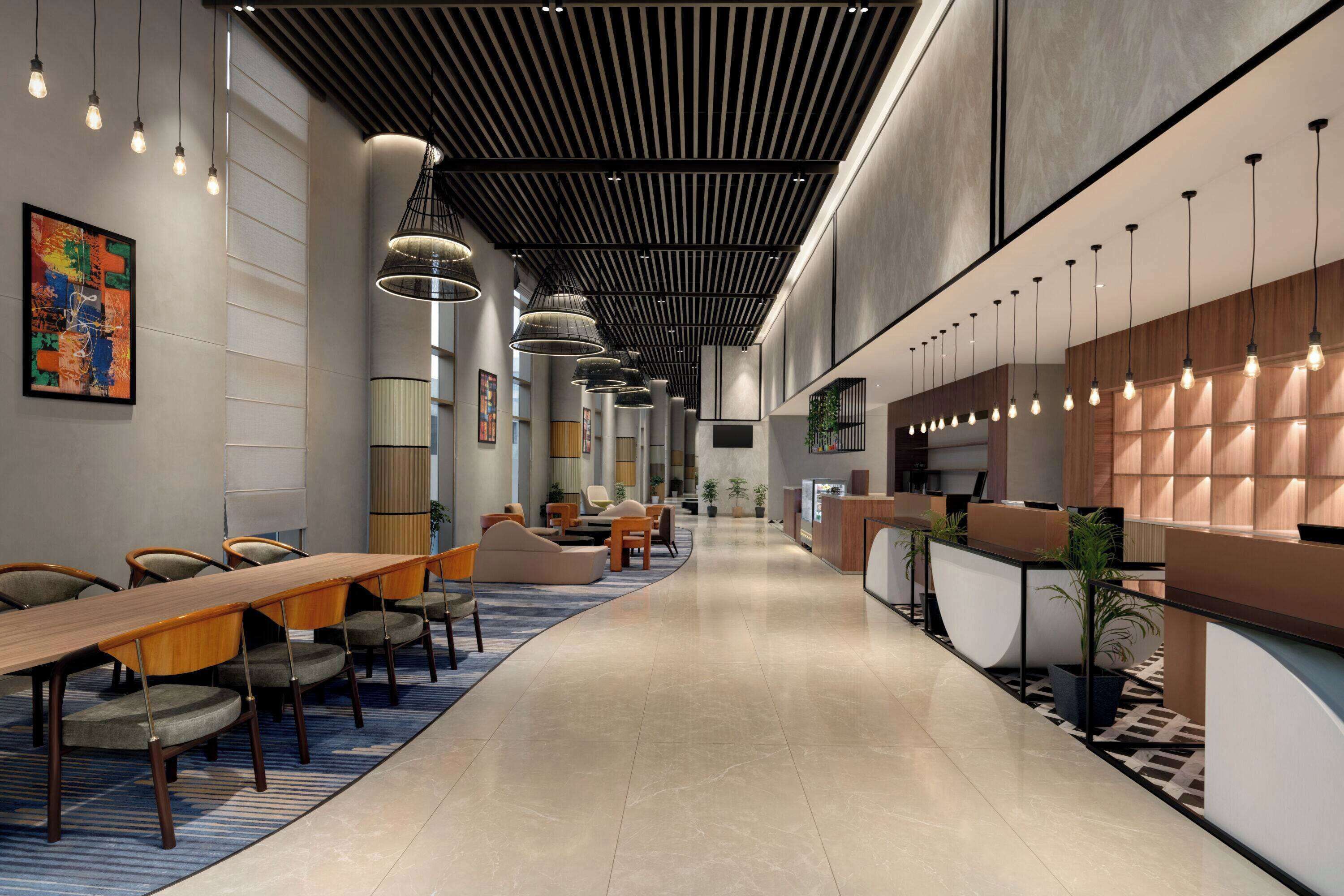 A modern hotel lobby with a long reception desk, seating area, and a large abstract painting on the wall.
