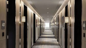 A hotel hallway with a carpeted floor, doors numbered 407 and 406, and wall-mounted lamps. - Ramada Encore By Wyndham Bhiwadi Phool Bagh Chowk (Tijara)