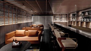 A modern bar area with leather seating, a long counter, and shelves with bottles. - Ramada Encore By Wyndham Bhiwadi Phool Bagh Chowk (Tijara)