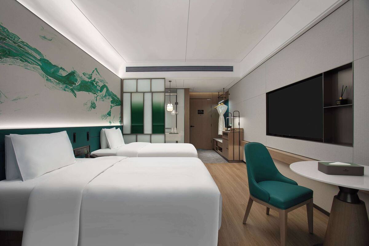 Une chambre d’hôtel moderne équipée de deux lits, d’un bureau, d’une chaise et d’un téléviseur.