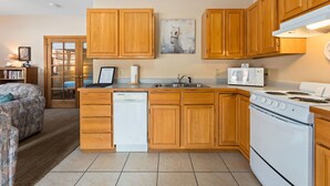 Una cocina con armarios de madera, lavavajillas, microondas y estufa.