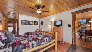 Ein rustikaler Raum mit einem Holzbett, einem Deckenventilator, einem Fernseher und einem Steinkamin.