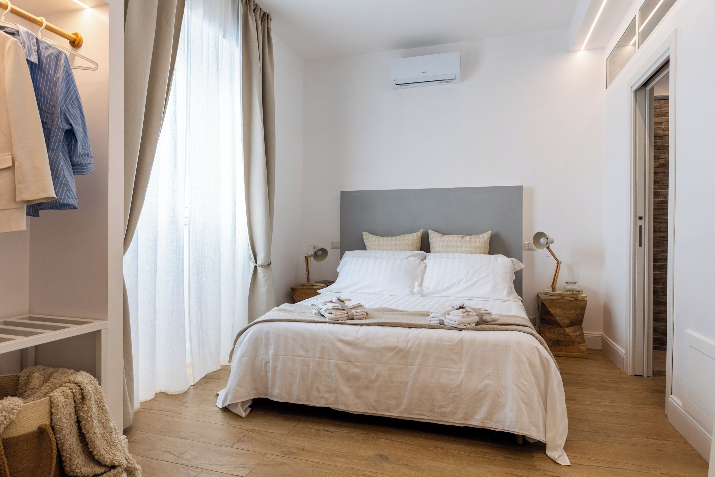 A bedroom with a bed, bedside tables, a wardrobe, and a window with curtains.