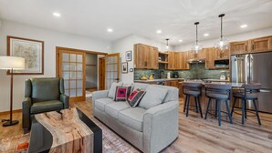 A modern kitchen with wooden cabinets, a stainless steel refrigerator, and bar stools.