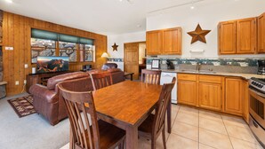 Une cuisine moderne avec des meubles en bois, un coin repas comprenant une table et des chaises en bois, et une grande fenêtre offrant une vue panoramique.